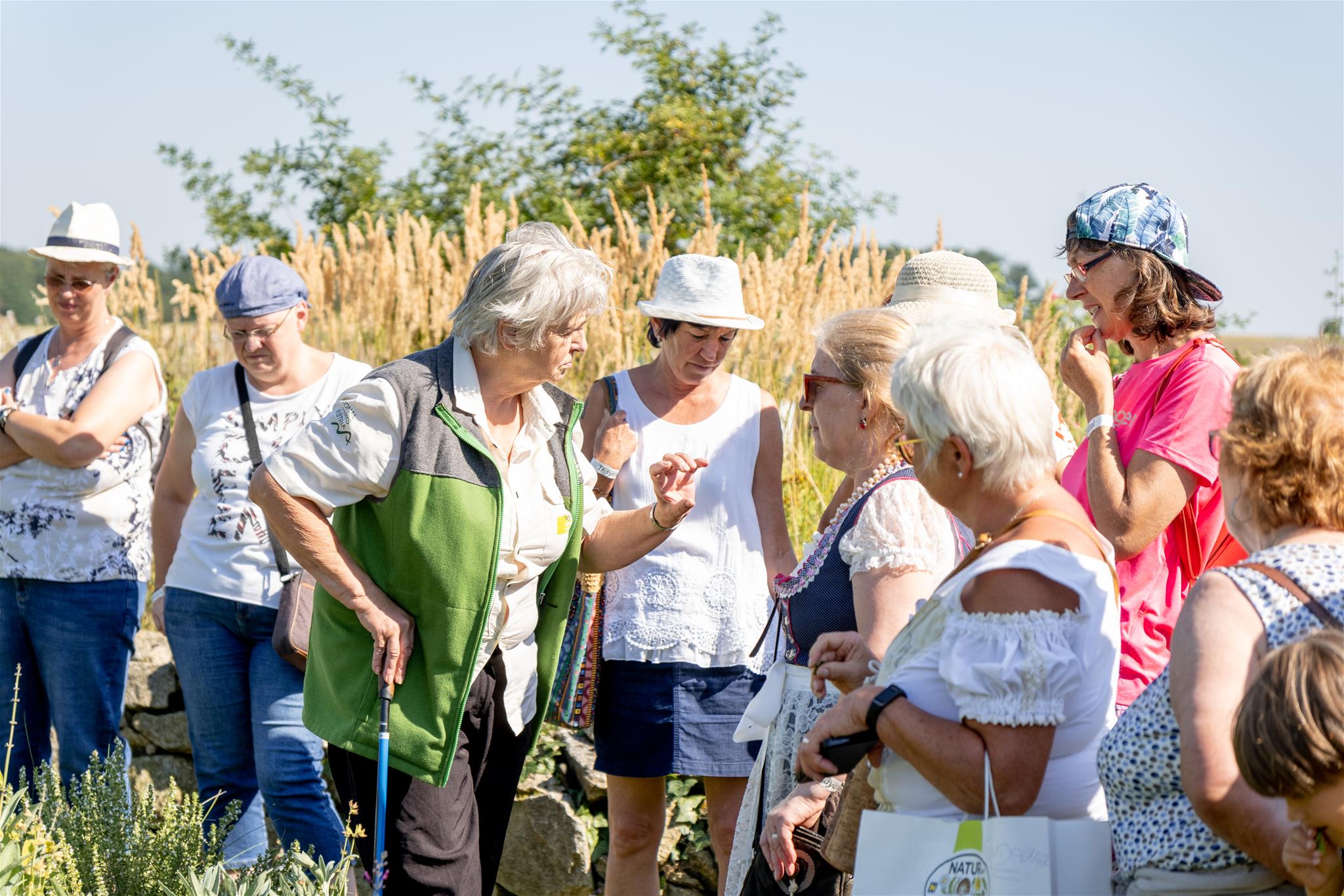 Kräuterhexe Helga mit ihren Besucher:innen im Kräutergarten